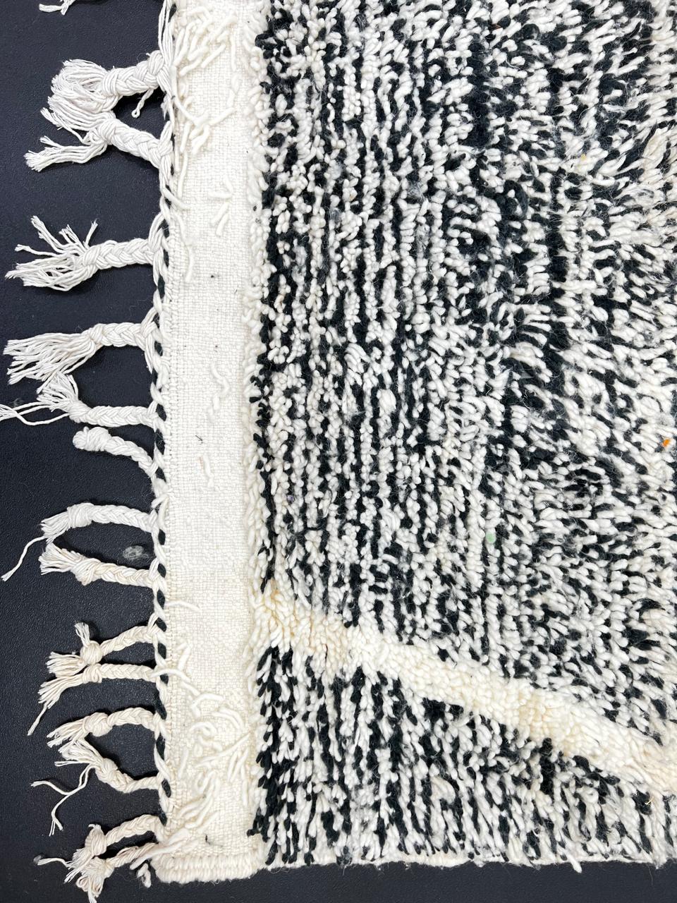 Black and white Moroccan wool runner rug with geometric diamond pattern and tassels, handmade by Berber artisans