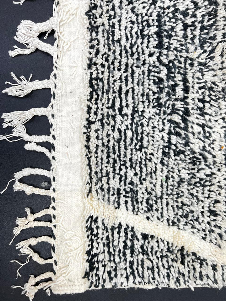 Black and white Moroccan wool runner rug with geometric diamond pattern and tassels, handmade by Berber artisans