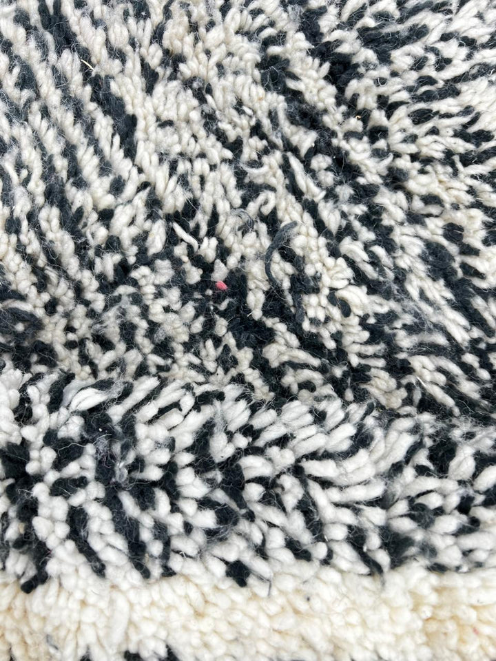 Black and white Moroccan wool runner rug with geometric diamond pattern and tassels, handmade by Berber artisans