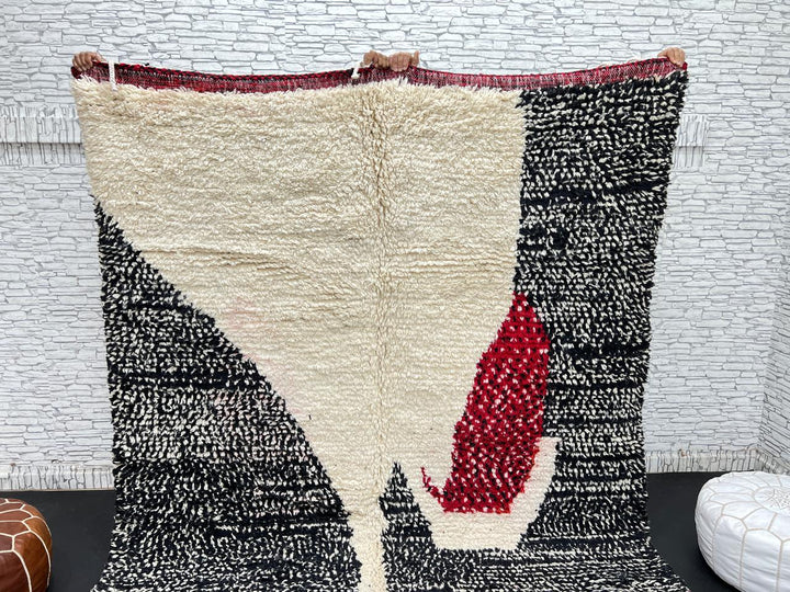 Handmade Moroccan wool rug with abstract black, cream, and red geometric design