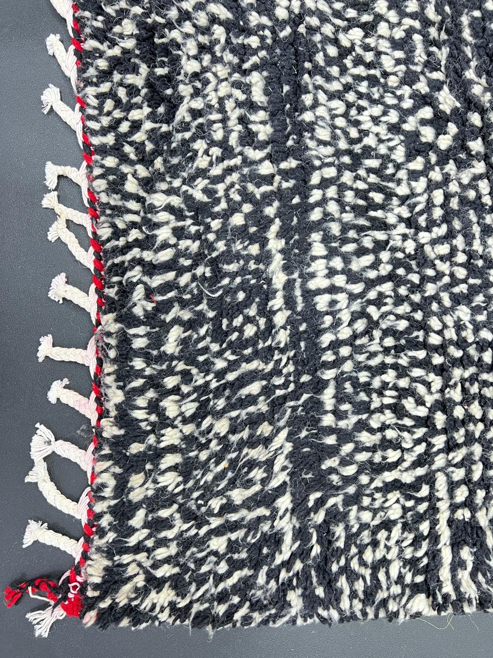 Handmade Moroccan wool rug with abstract black, cream, and red geometric design