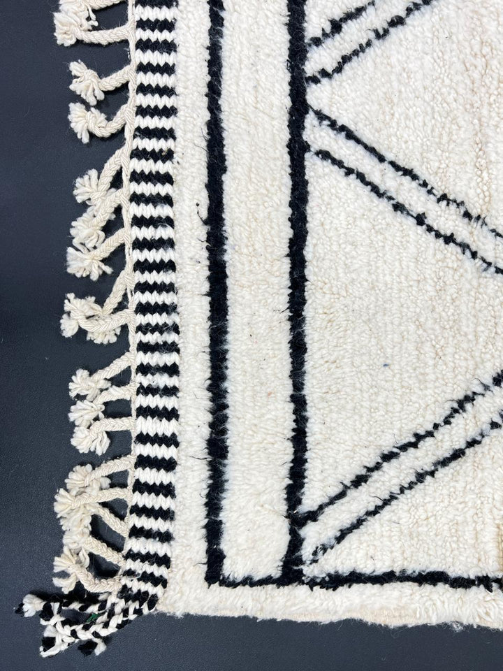 Black and white handmade Beni Ourain Moroccan wool rug with geometric diamond design and fringed edges