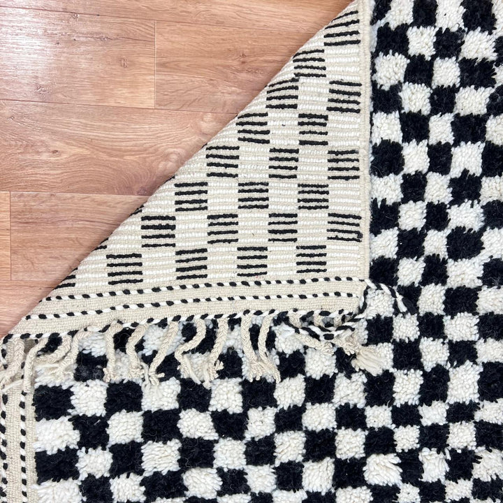 Handmade Moroccan wool rug with black and white checkered design. Plush shag texture, modern style, and artisan crafted.