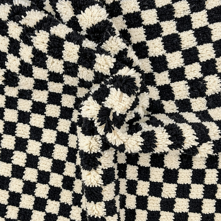 Handmade Moroccan wool rug with black and white checkered design. Plush shag texture, modern style, and artisan crafted.
