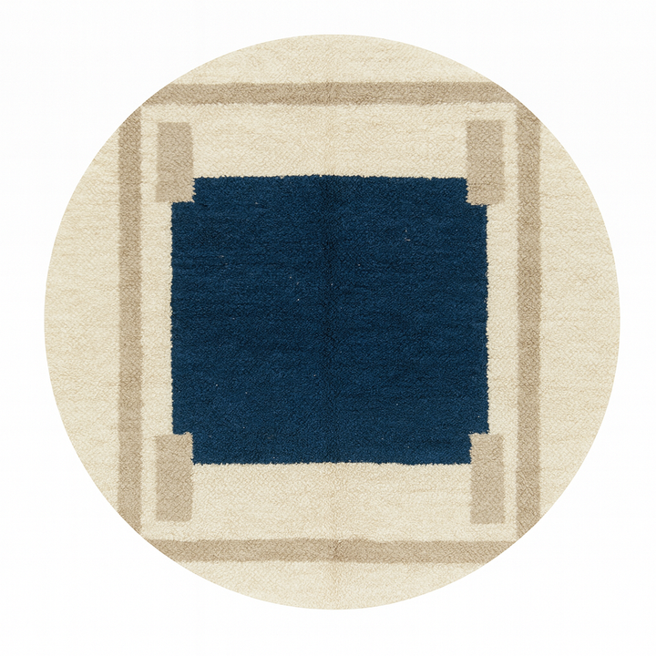 Round Moroccan wool rug with a navy blue center and beige geometric border.