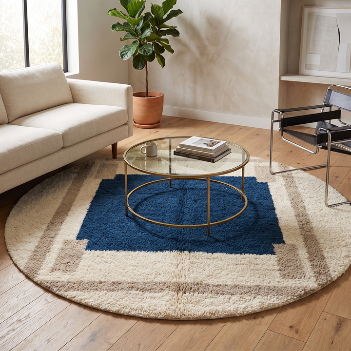 Round Moroccan wool rug with a navy blue center and beige geometric border.