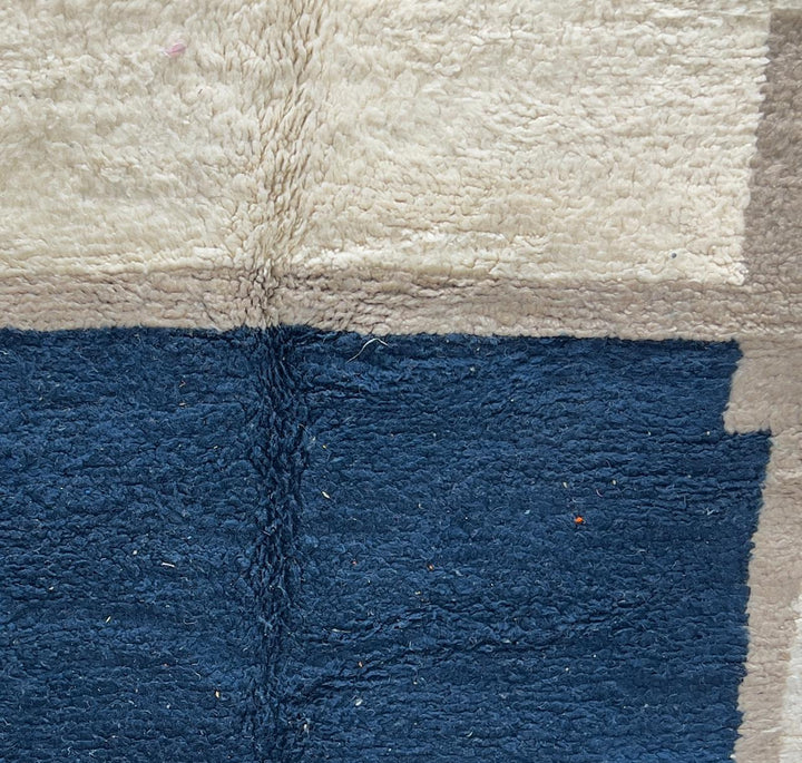 Round Moroccan wool rug with a navy blue center and beige geometric border.