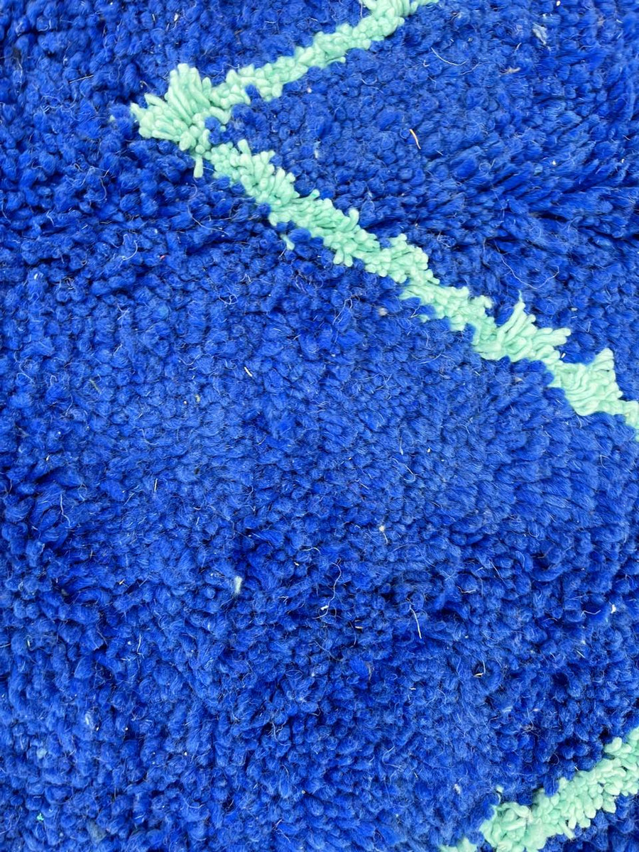 Round Moroccan wool rug in deep blue with light blue geometric Berber patterns on a white background