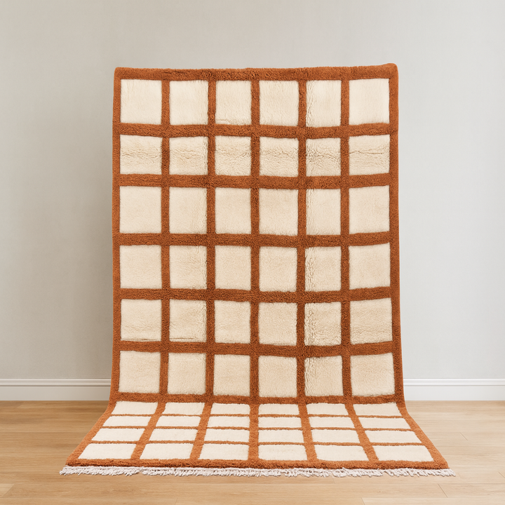 Rug with grid pattern on a wooden floor against a white wall