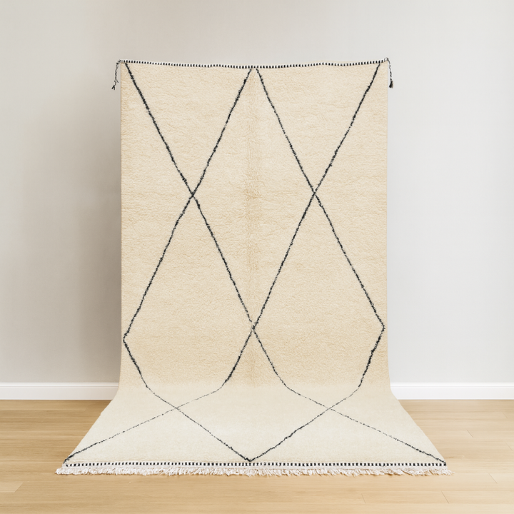 Beige rug with black geometric pattern on a wooden floor and light-colored wall background