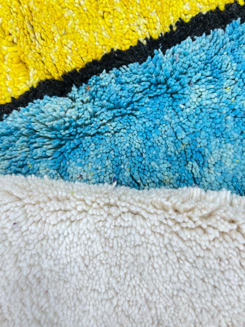 Handwoven Moroccan wool rug with bold geometric color blocks in blue, yellow, and red
