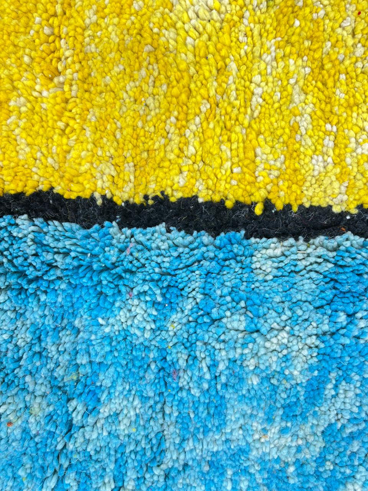 Handwoven Moroccan wool rug with bold geometric color blocks in blue, yellow, and red