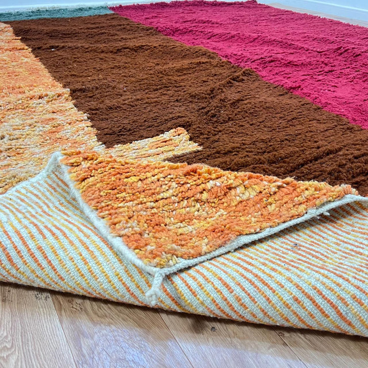 Modern handmade Moroccan wool rug with bold color-block design. Thick shag texture, artistic style, and ethically crafted in Morocco.