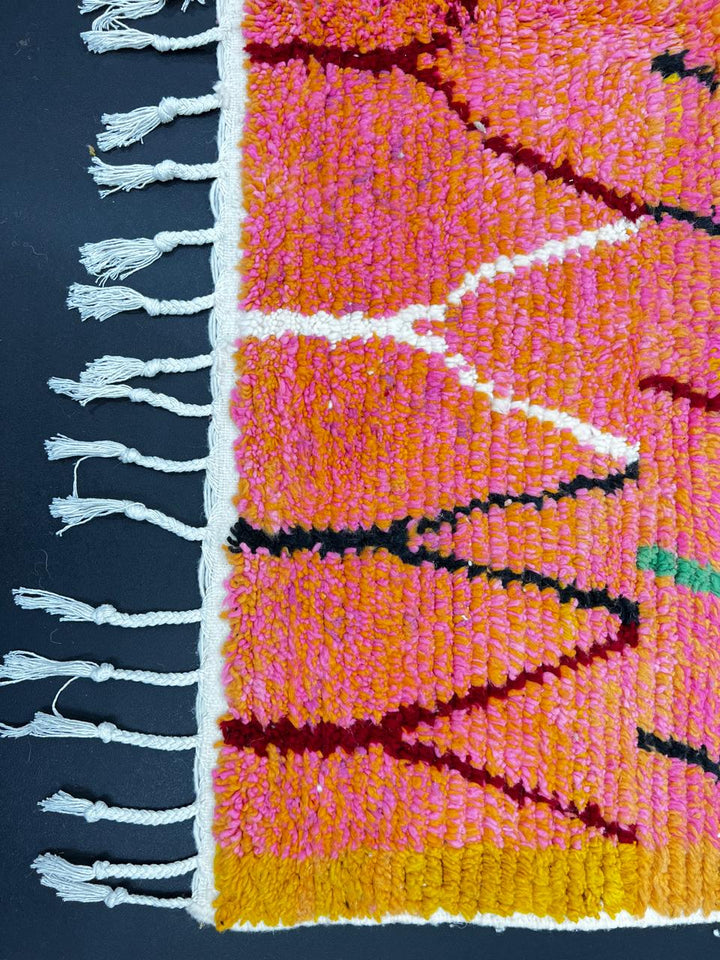 Handmade colorful Moroccan runner rug with abstract geometric design in orange, pink, green, and earthy tones, crafted from natural wool by Berber artisans.