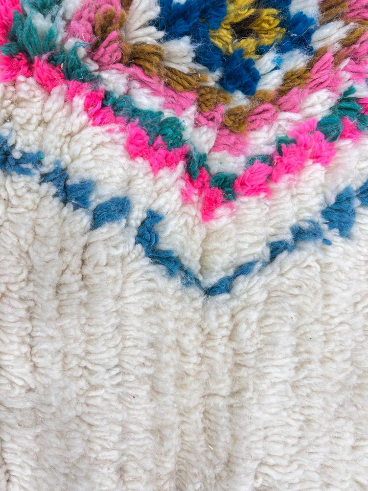 Colorful handmade Moroccan Berber rug with diamond tribal patterns on white wool