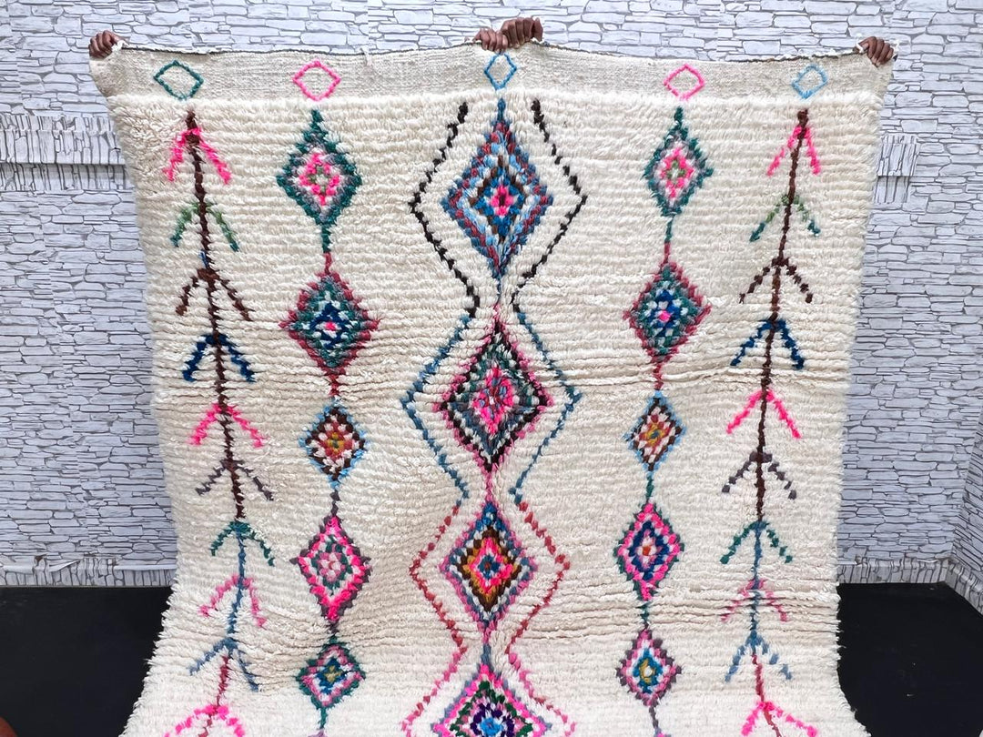 Colorful handmade Moroccan Berber rug with diamond tribal patterns on white wool