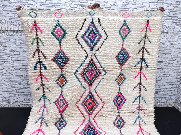 Colorful handmade Moroccan Berber rug with diamond tribal patterns on white wool