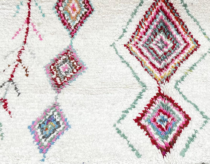 Handmade Moroccan wool runner rug with colorful diamond and arrow Berber motifs on a white background