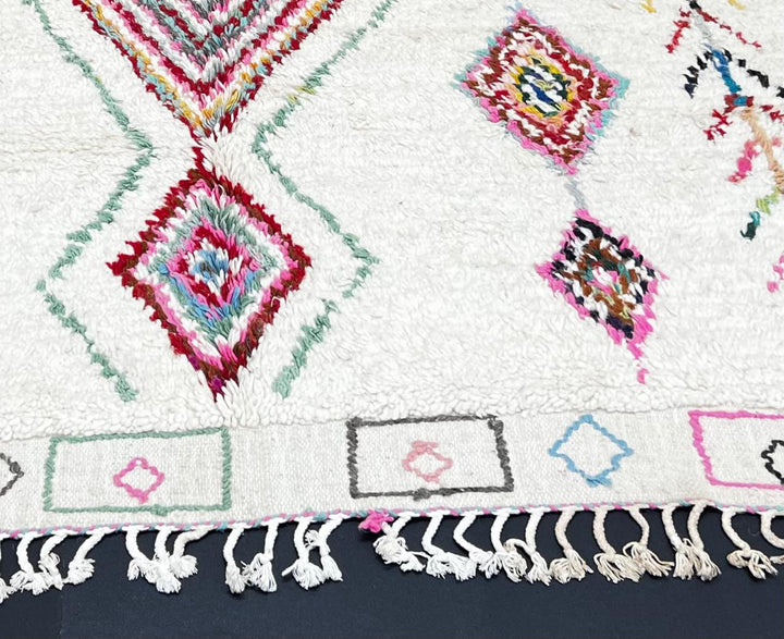 Handmade Moroccan wool runner rug with colorful diamond and arrow Berber motifs on a white background