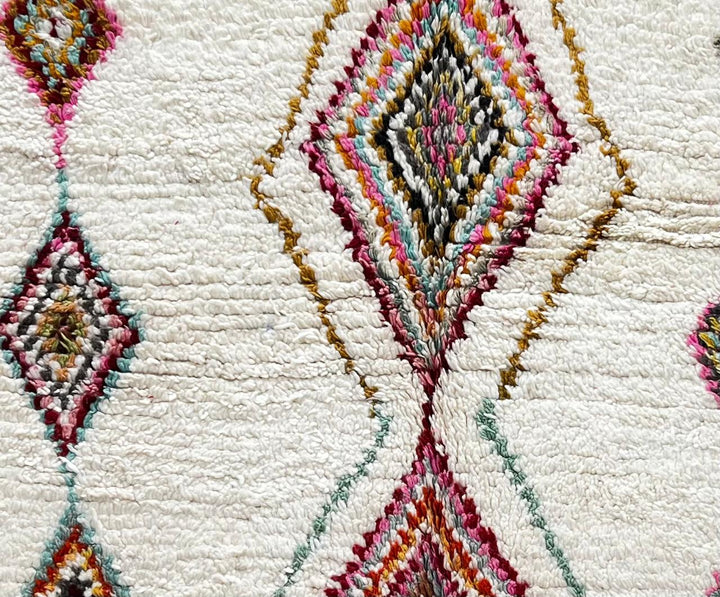 Handmade Moroccan wool runner rug with colorful diamond and arrow Berber motifs on a white background