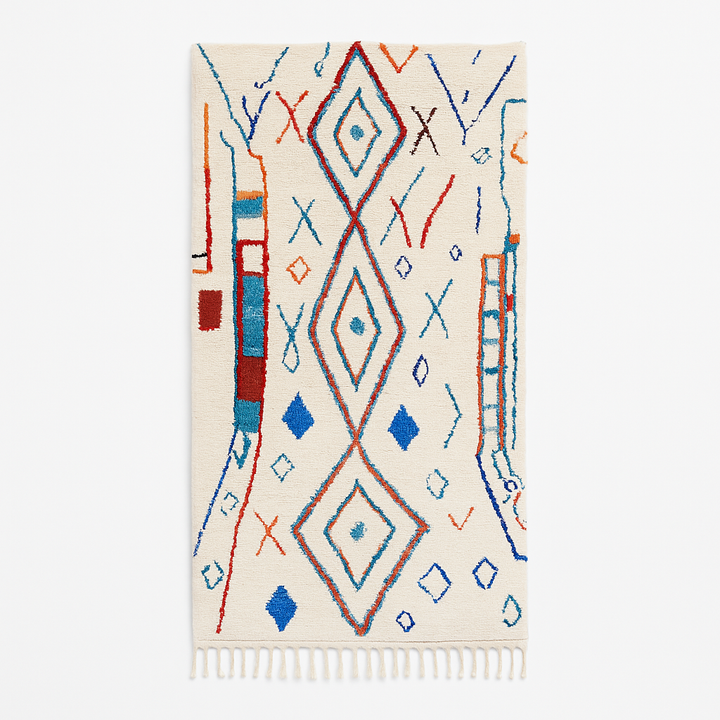 Handmade colorful Moroccan wool runner rug with blue, red, and orange geometric diamond patterns on a white base.