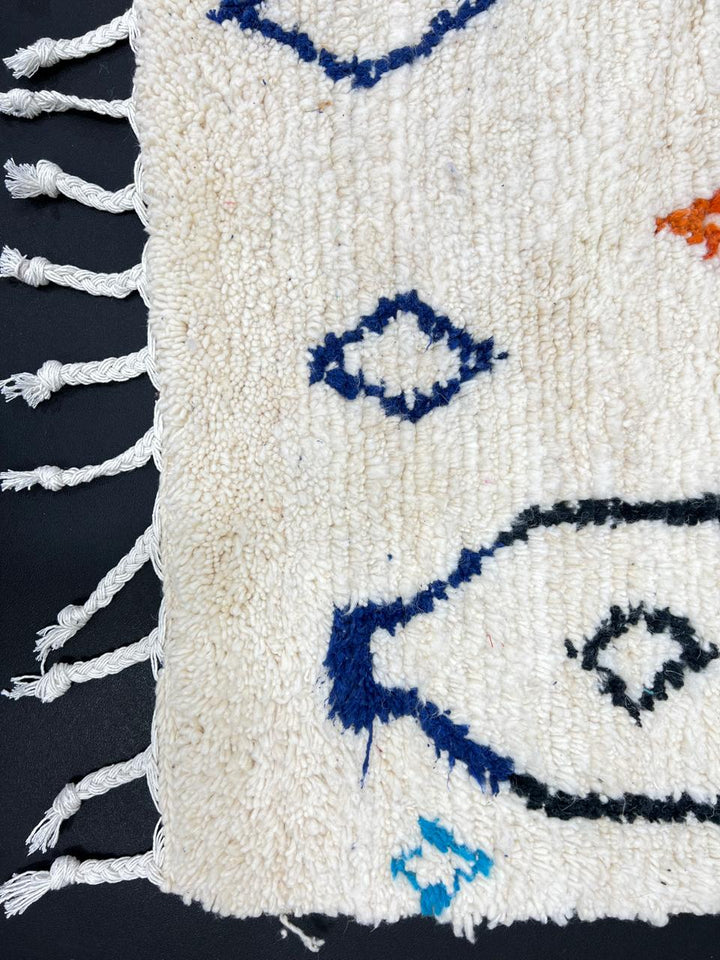 Handmade colorful Moroccan wool runner rug with blue, red, and orange geometric diamond patterns on a white base.