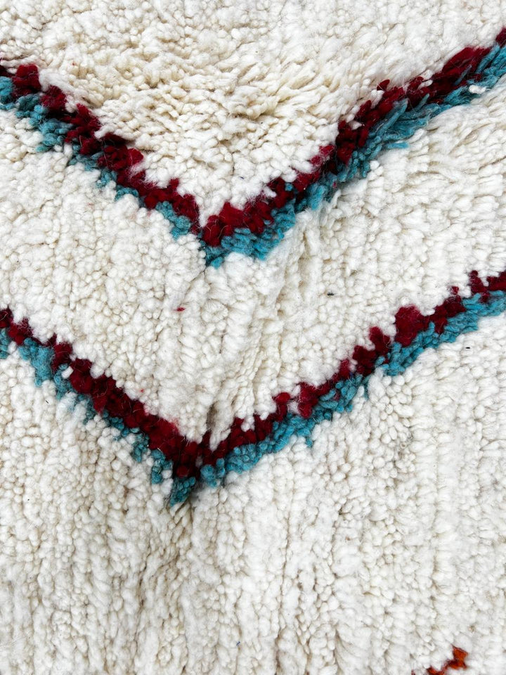 Handmade colorful Moroccan wool runner rug with blue, red, and orange geometric diamond patterns on a white base.