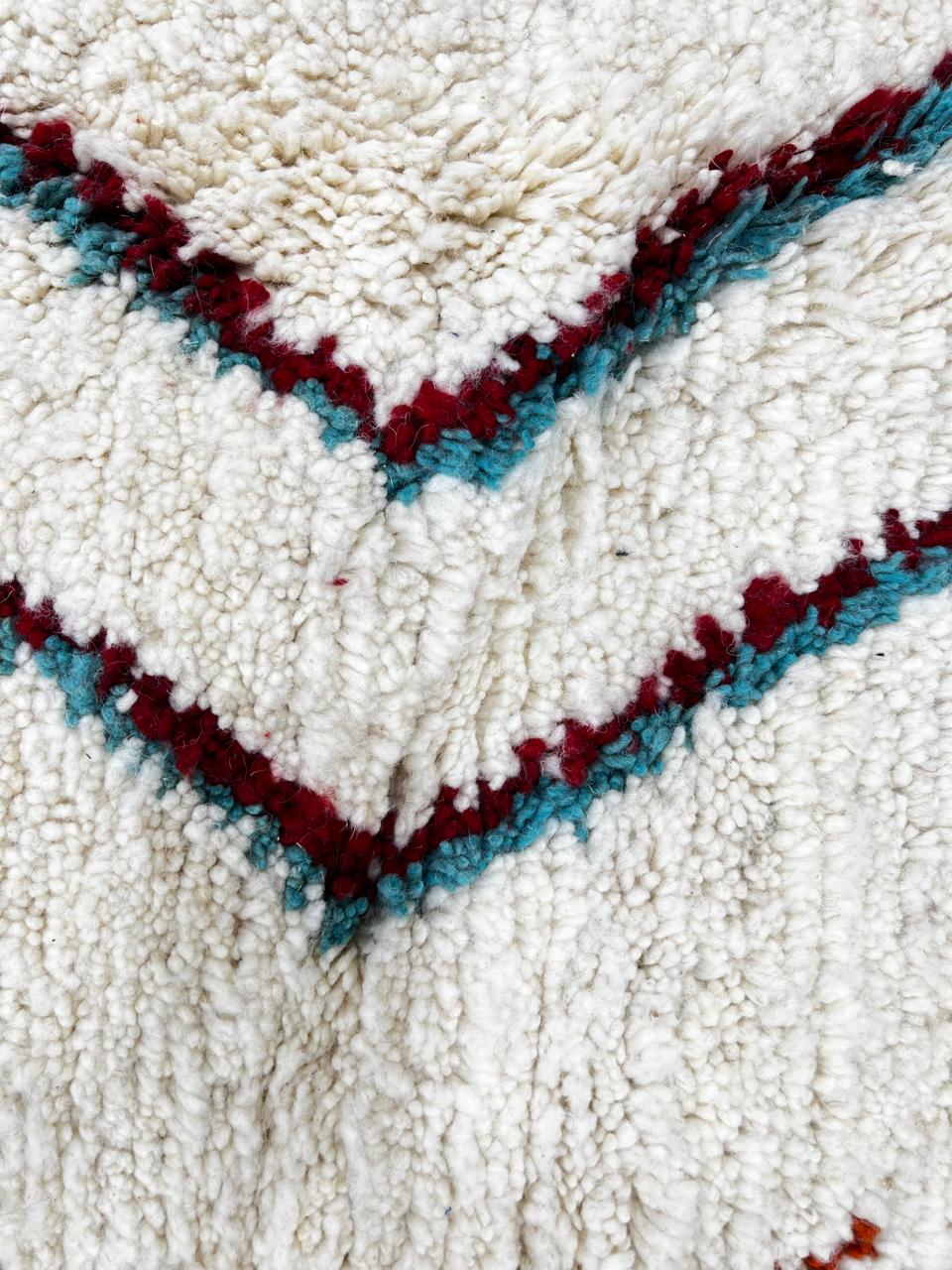 Handmade colorful Moroccan wool runner rug with blue, red, and orange geometric diamond patterns on a white base.