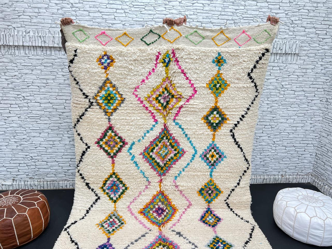 Colorful handmade Moroccan Berber wool rug with vibrant diamond patterns on ivory background