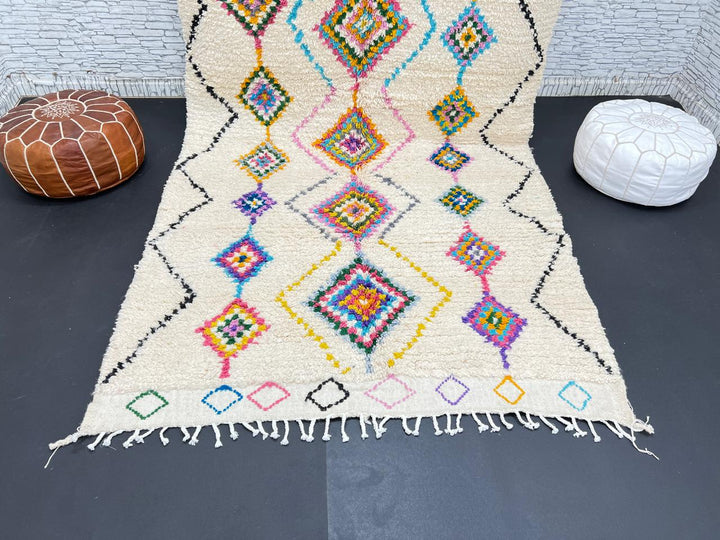 Colorful handmade Moroccan Berber wool rug with vibrant diamond patterns on ivory background