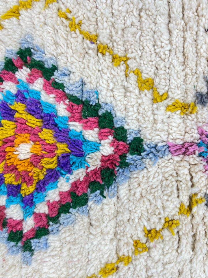 Colorful handmade Moroccan Berber wool rug with vibrant diamond patterns on ivory background