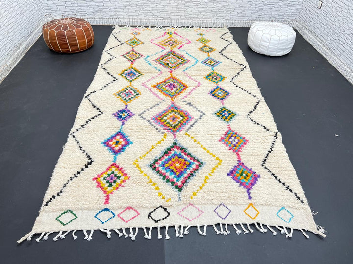 Colorful handmade Moroccan Berber wool rug with vibrant diamond patterns on ivory background