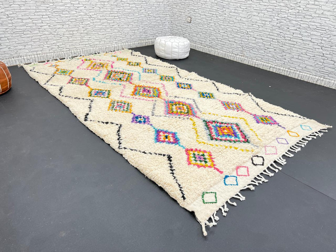 Colorful handmade Moroccan Berber wool rug with vibrant diamond patterns on ivory background