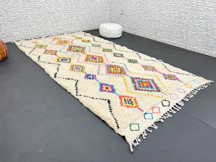 Colorful handmade Moroccan Berber wool rug with vibrant diamond patterns on ivory background