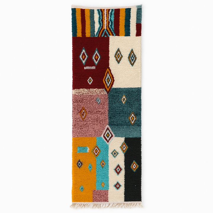 Handmade colorful Moroccan runner rug with patchwork blocks in burgundy, teal, mustard, cream, black, and turquoise featuring diamond Berber motifs.