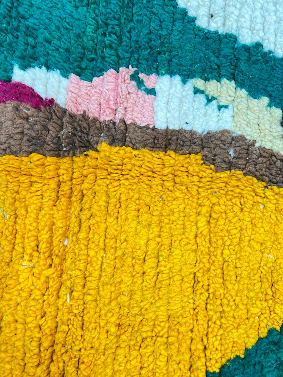 Handwoven colorful Moroccan wool rug with abstract geometric design in pink, yellow, green, and black tones