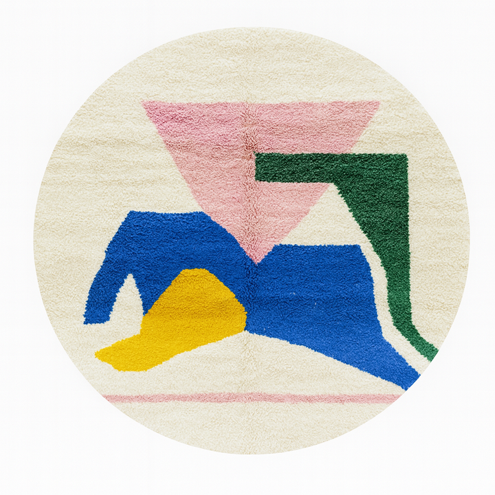 Round colorful Moroccan wool rug with abstract geometric shapes in pink, green, blue, and yellow.