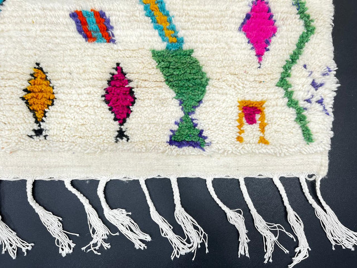 Handwoven colorful Moroccan wool rug with geometric Berber motifs on ivory background