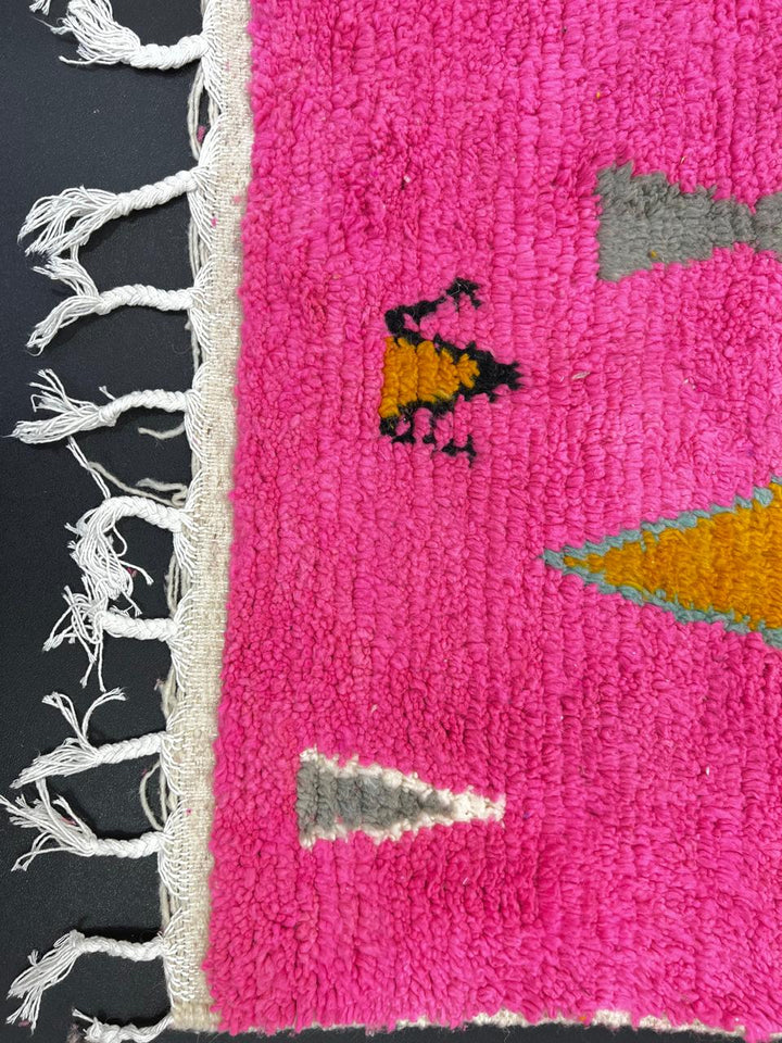 Handwoven colorful Moroccan wool rug with pink base and abstract blue, green, orange, and gold tribal motifs