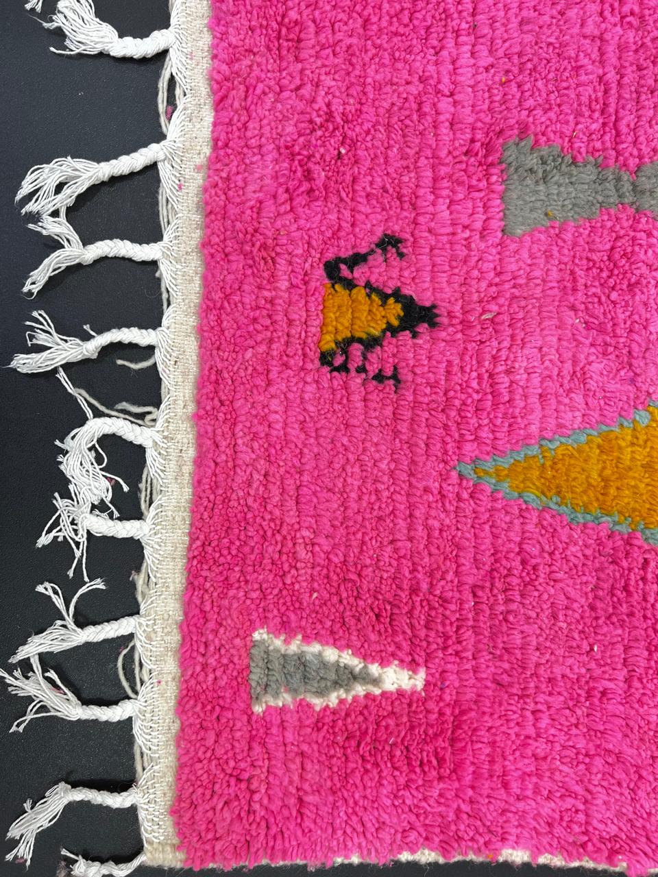 Handwoven colorful Moroccan wool rug with pink base and abstract blue, green, orange, and gold tribal motifs