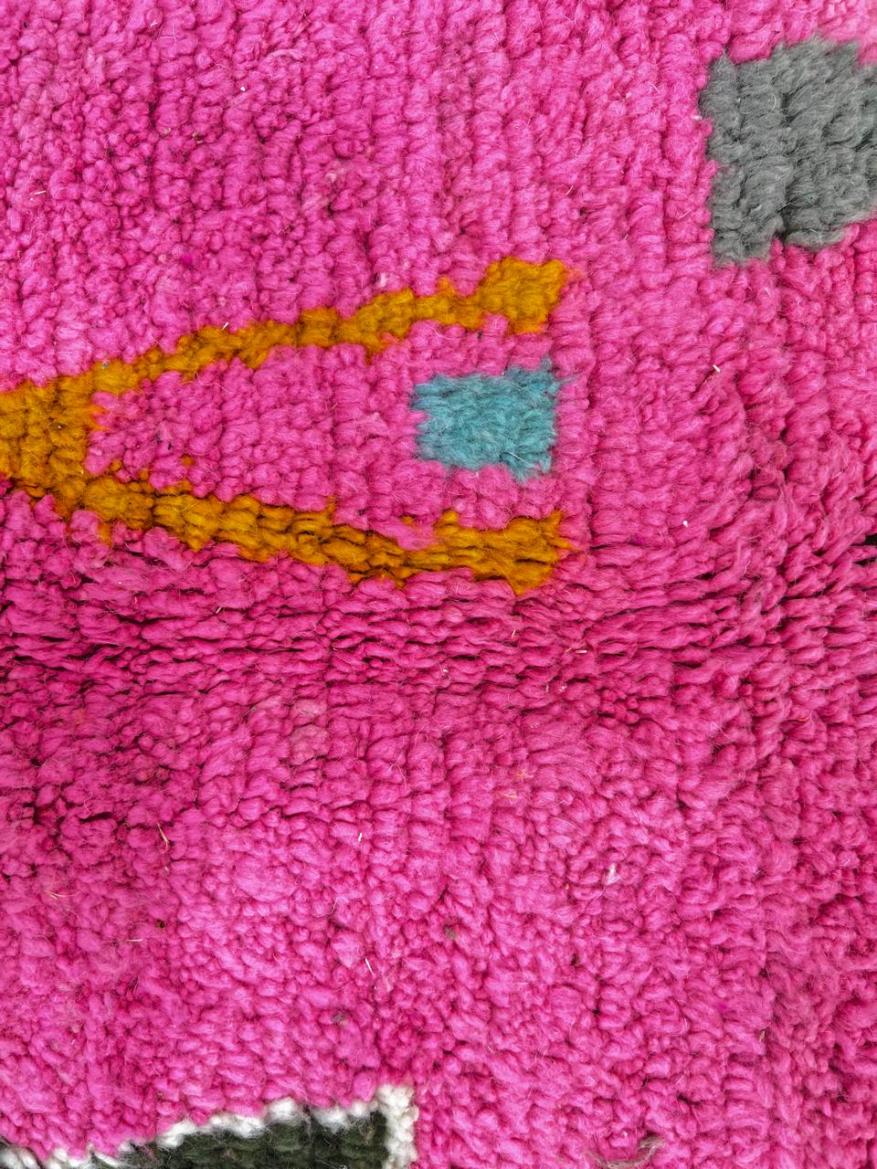 Handwoven colorful Moroccan wool rug with pink base and abstract blue, green, orange, and gold tribal motifs