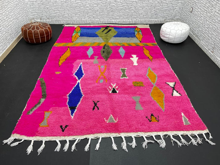 Handwoven colorful Moroccan wool rug with pink base and abstract blue, green, orange, and gold tribal motifs