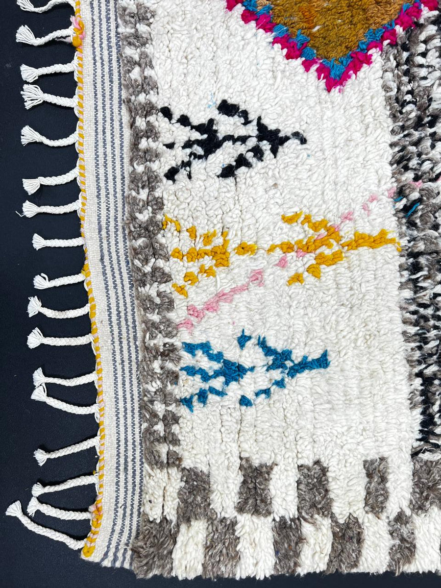 Handmade colorful Moroccan wool runner rug with geometric tribal patterns in pink, yellow, blue, green, and black on a white base.