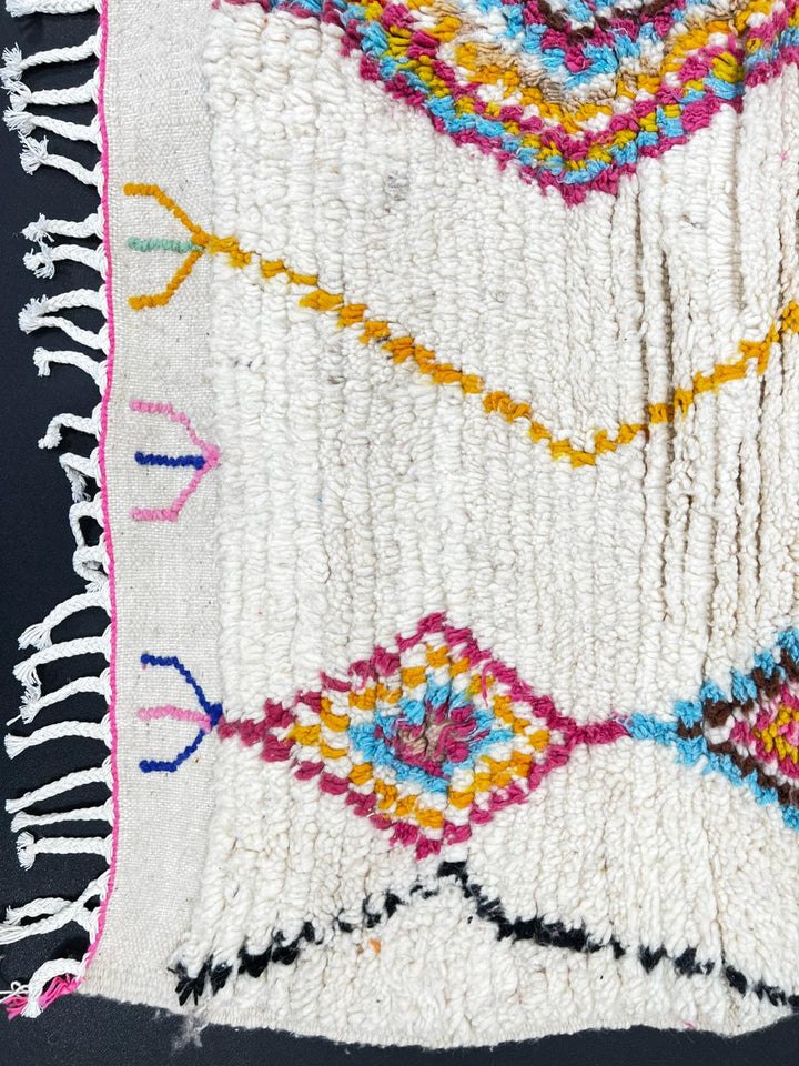 Handmade Moroccan runner rug with colorful diamond patterns on a white  background, crafted from natural wool by Berber artisans.
