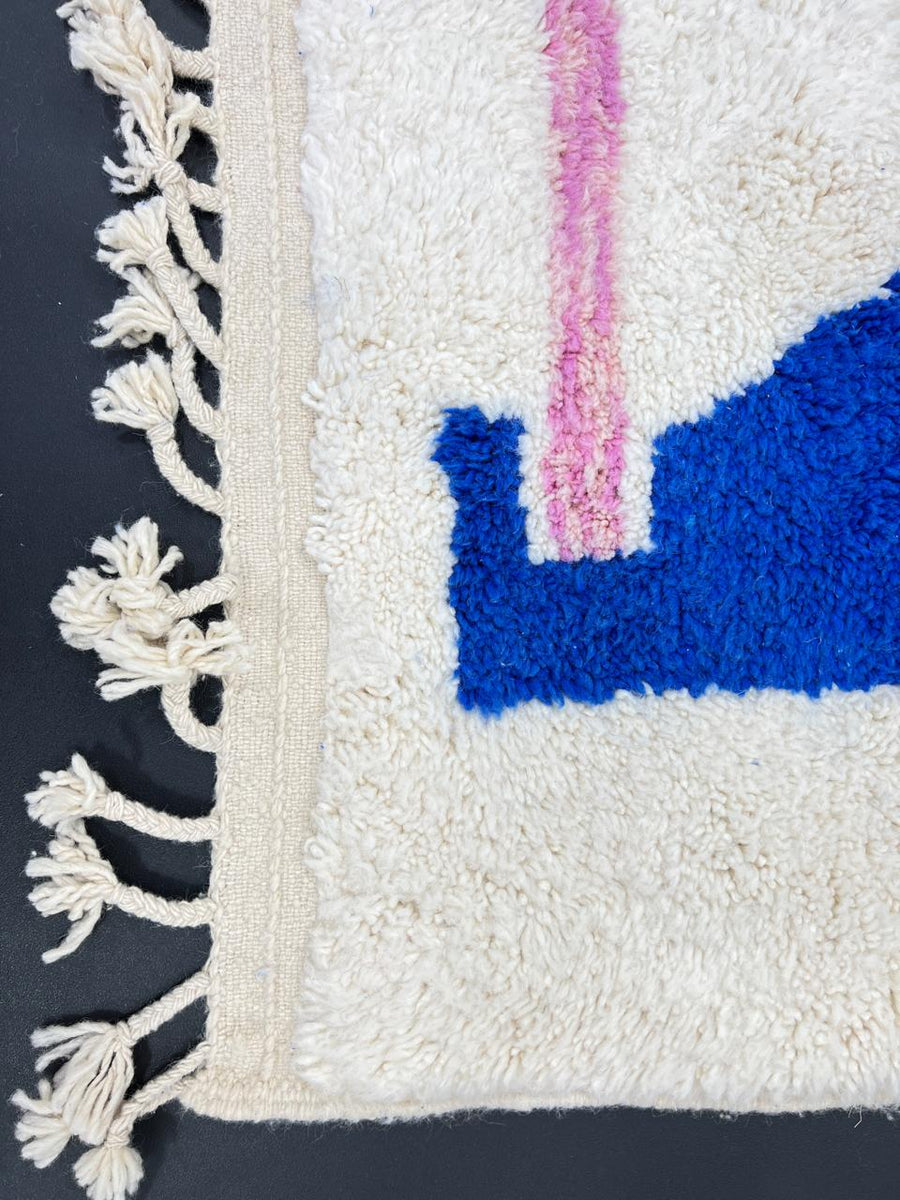 Colorful geometric Moroccan wool runner rug with abstract shapes in pink, blue, green, and yellow on a cream base