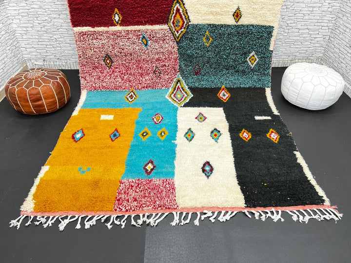 Colorful Moroccan wool rug with geometric patchwork and Berber motifs in red, turquoise, yellow, and black