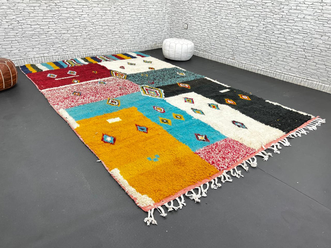 Colorful Moroccan wool rug with geometric patchwork and Berber motifs in red, turquoise, yellow, and black