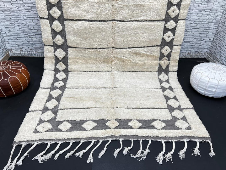 Cream Moroccan wool rug with charcoal gray geometric border and linear Berber pattern