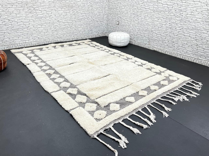 Cream Moroccan wool rug with charcoal gray geometric border and linear Berber pattern