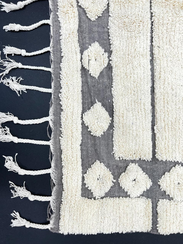 Cream Moroccan wool rug with charcoal gray geometric border and linear Berber pattern